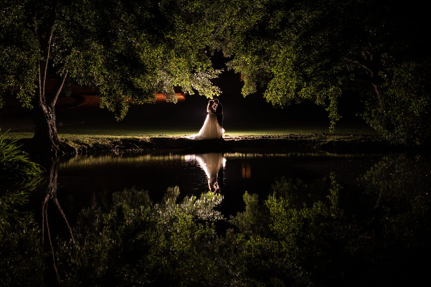 Beautiful night portrait of bride and grooms reflected in lake at night